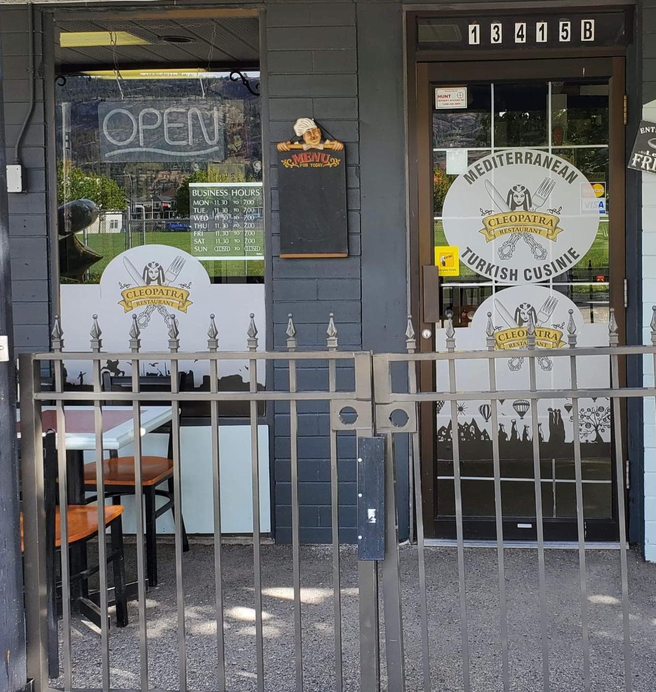 Cleopatra's front door with the neon OPEN sign, business hours, and the 'Mediterranean · Turkish Cuisine' window logos at 13415B